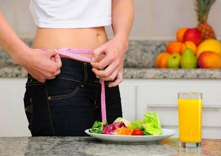 A girl who loses weight while on a diet measures her waist size